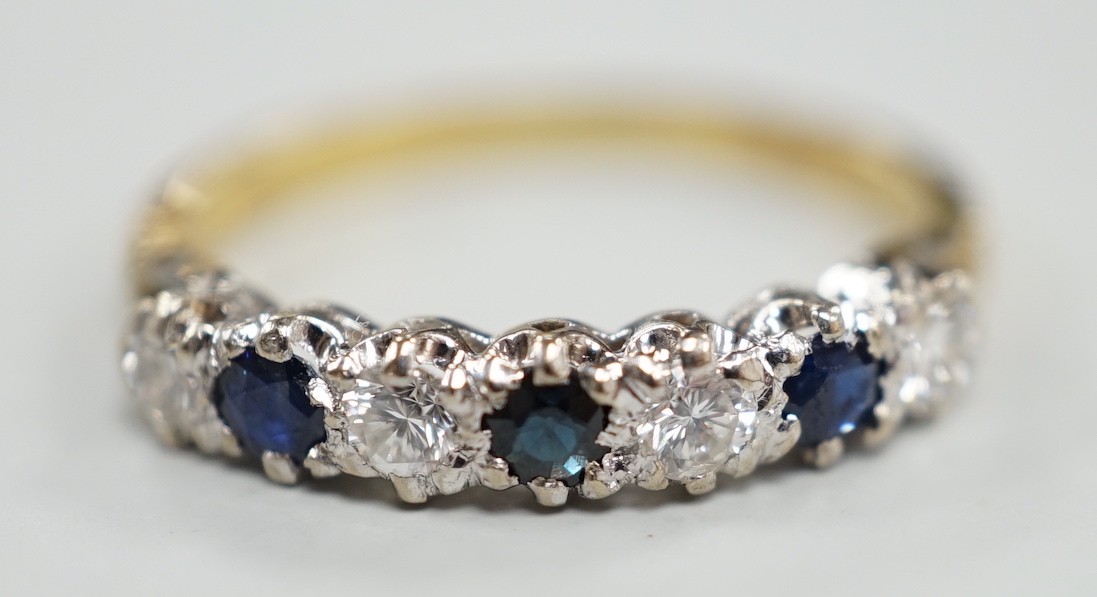 A modern 18ct gold, three stone sapphire and four stone diamond set half hoop ring, size P/Q, gross weight 2.9 grams.